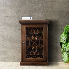 a wooden cabinet with candles on it next to a potted plant and concrete wall