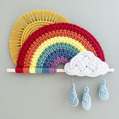 there is a crocheted rainbow and two baby booties hanging on the wall