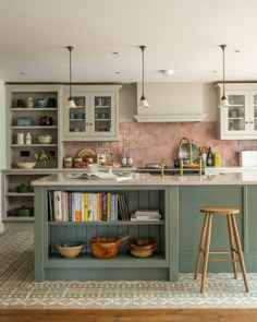 a kitchen with an island and bookshelf in the center, along with two stools