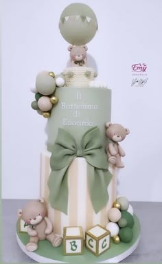 a baby shower cake with teddy bears and blocks on the bottom tier, in pastel green