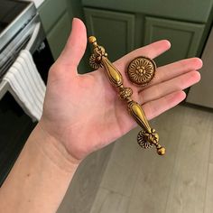 a person holding two gold colored rings in their hand with an oven in the background