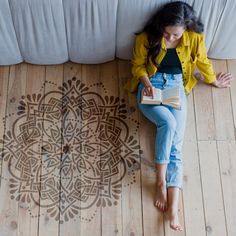 a woman is sitting on the floor with her book and looking down at it while reading