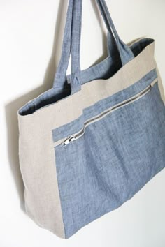 a blue and white tote bag hanging on the wall with zippers in it