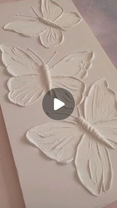 some white butterflies are on top of a piece of paper and it is being made