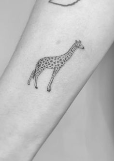 a small giraffe tattoo on the arm