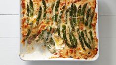 a casserole dish with green asparagus and cheese on the top, ready to be eaten