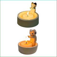 two candles with cat figurines sitting on top of one candle and another in the middle