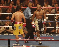 two men standing next to each other in a boxing ring with referee and crowd watching