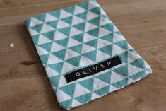 a teal and white patterned cloth with the name oliver written in black on it