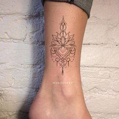 a woman's foot with a tattoo design on the side of her leg,