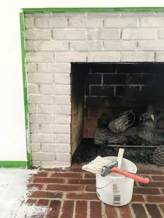 a brick fireplace that has been painted white and is being worked on with paint rollers