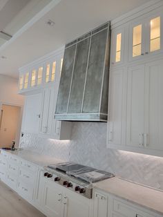 a large kitchen with white cabinets and marble counter tops on the island in front of an oven