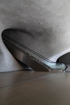 an escalator in the middle of a building with concrete walls and flooring