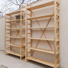 two wooden shelves sitting next to each other on the side of a building with trees in the background