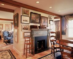 a living room filled with furniture and a fire place in front of a fireplace covered in pictures