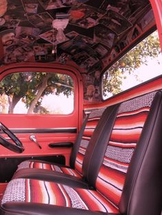 the interior of an old red truck with pictures on the ceiling and leather seat covers