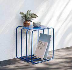 a blue table with a book on it and a potted plant next to it