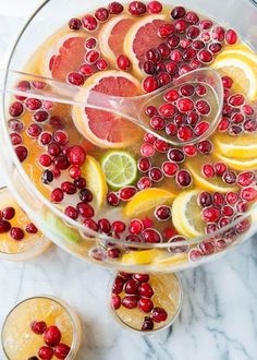 a bowl filled with oranges and cranberries on top of a marble counter