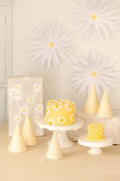 a table topped with yellow and white cakes covered in frosting next to paper snowflakes