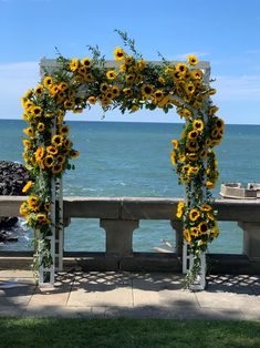 the sunflowers are arranged in an arch by the water's edge for a wedding ceremony