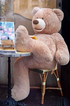 a large teddy bear sitting at a small table