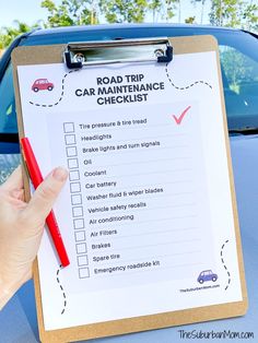 a hand holding a clipboard with a road trip checklist on it next to a car