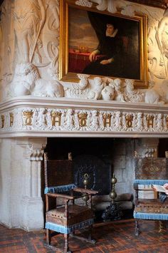 an ornate fireplace with two chairs and a painting on the wall