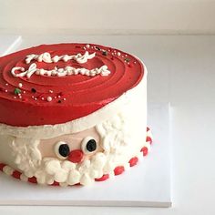 a cake decorated to look like santa claus is on a white plate with red icing and sprinkles