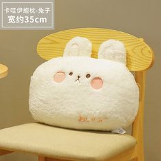 a white stuffed animal sitting on top of a wooden chair next to a yellow table