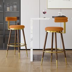 two modern bar stools in front of a white table with wine glasses on it