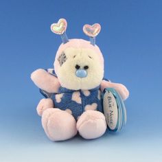 a pink teddy bear with blue and white polka dots on it's chest, sitting against a blue background