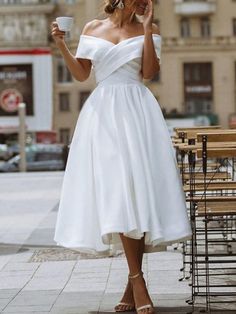 a woman wearing a white dress and holding a cup