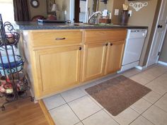 a kitchen with tile flooring and wooden cabinetry next to a dishwasher