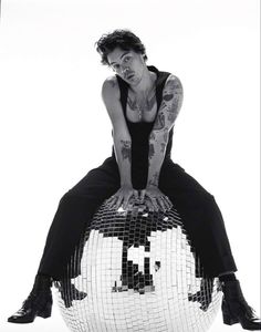 a woman sitting on top of a disco ball with her hands on the back of it