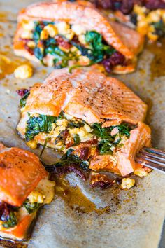 a piece of salmon with spinach and corn on it is being eaten by a fork