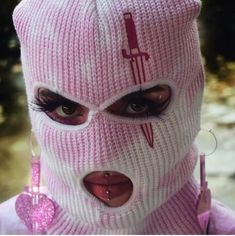 a woman wearing a pink knitted mask with scissors on it's face and nose