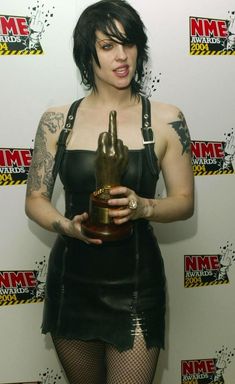 a woman with tattoos holding an award in her hand