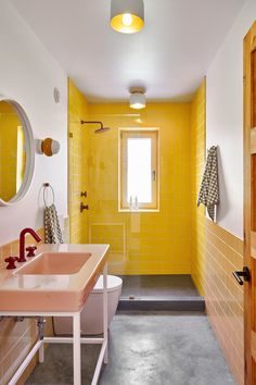 a bathroom with yellow tiles and pink sinks