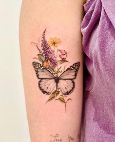 a woman's arm with a butterfly and flowers tattoo on the left side of her arm