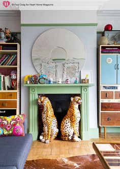 two cheetah statues sitting in front of a fireplace with bookshelves on either side