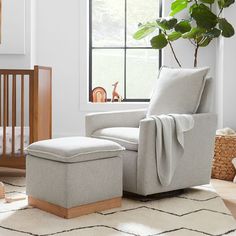 a baby's room with a crib, rocking chair and large potted plant