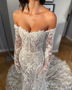 a woman in a white wedding dress standing on a wooden floor with her hands behind her back