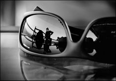 the reflection of two people in a rear view mirror on a table with other objects