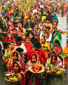 a large group of people standing around each other in front of a body of water