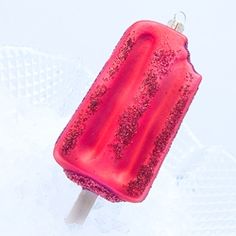 an ice lolly popsicle sitting on top of a white table with pink frosting