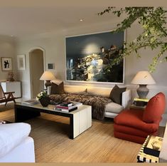 a living room filled with furniture and a painting on the wall above it's fireplace