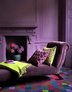 a living room filled with furniture and a fire place covered in purple walls next to a fireplace