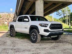 a white toyota truck parked under a bridge