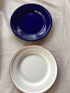 two blue and white plates sitting on top of a white tablecloth covered table cloth