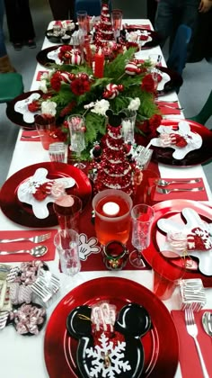 the table is set with red and white plates, silverware, and candy canes